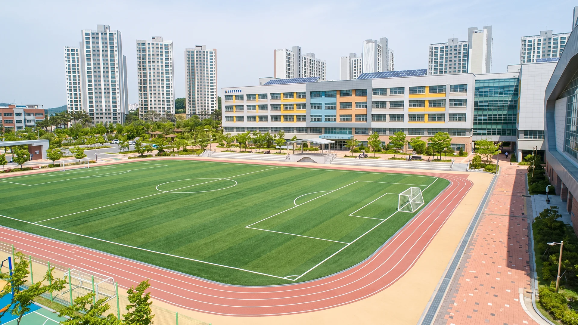 학교 건축물과 육상 트랙, 운동장 및 체육시설의 배치를 표현한 교육시설 건축 조감도